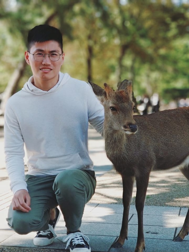Kevin crouching next to a young deer